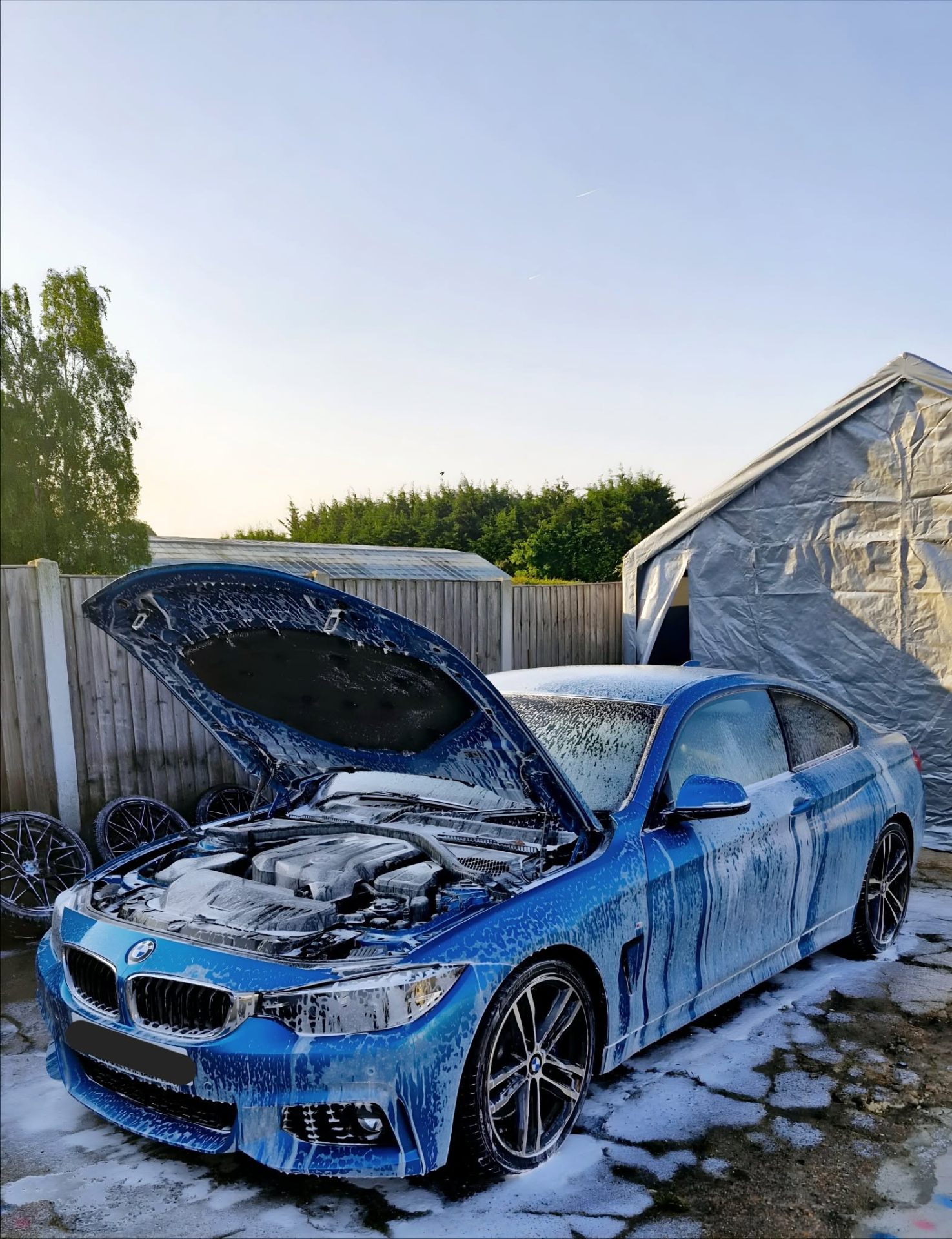 Blue BMW 4 Series covered in snow foam during exterior deep clean